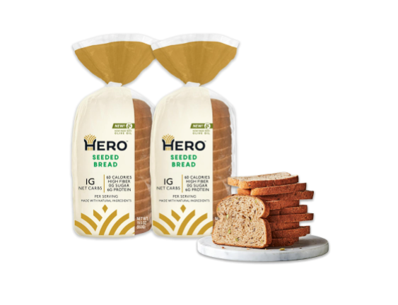 two loaves of sliced bread in plastic wrap with a stack of sliced bread on a plate next to it