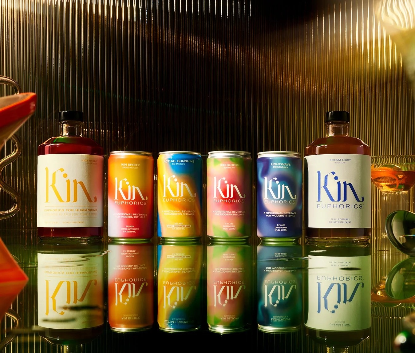 The lineup of non-alcoholic Kin Euphorics drinks with their reflections on a reflective surface. 