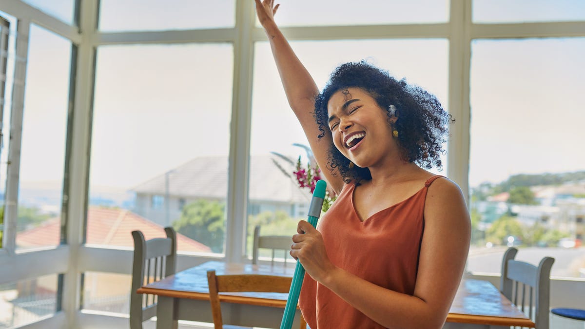 Woman singing and dancing while cleaning.