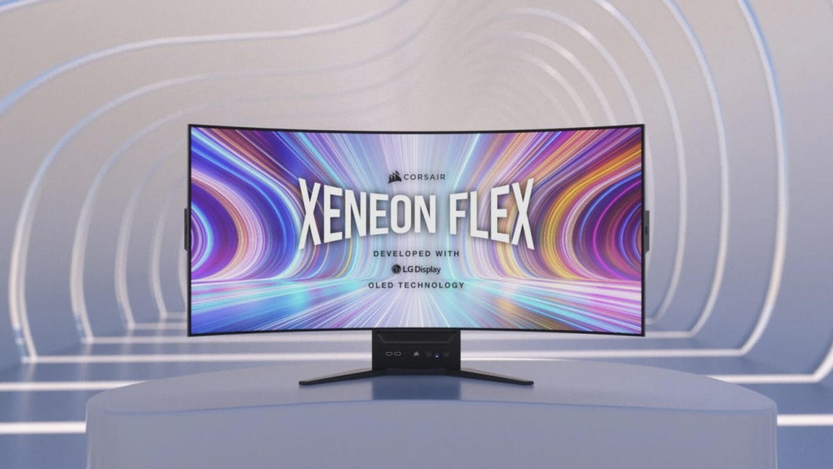 Corsair Xenon Flex gaming display on a large white pedestal with striations of white light on a tunnel of white walls