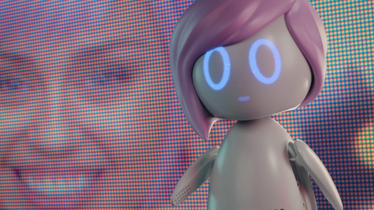 A woman with purple hair hold a small robot that also has plastic purple hair