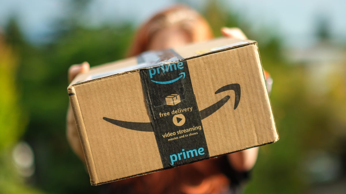 An Amazon cardboard shipping box being held by a person toward the camera.