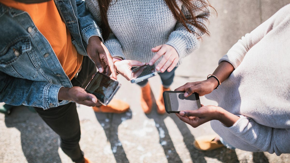 Three teenagers texting in a circle