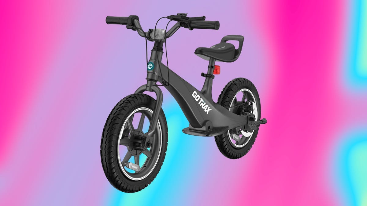 The GoTrax V14 electric balance bike for kids is displayed against a gradient red, yellow and green background.