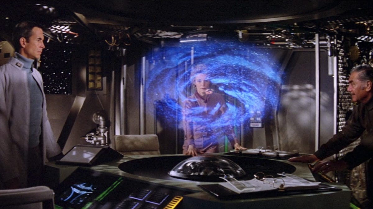 Three space travelers pensively consider a hologram of a black hole in The Black Hole on Disney Plus.