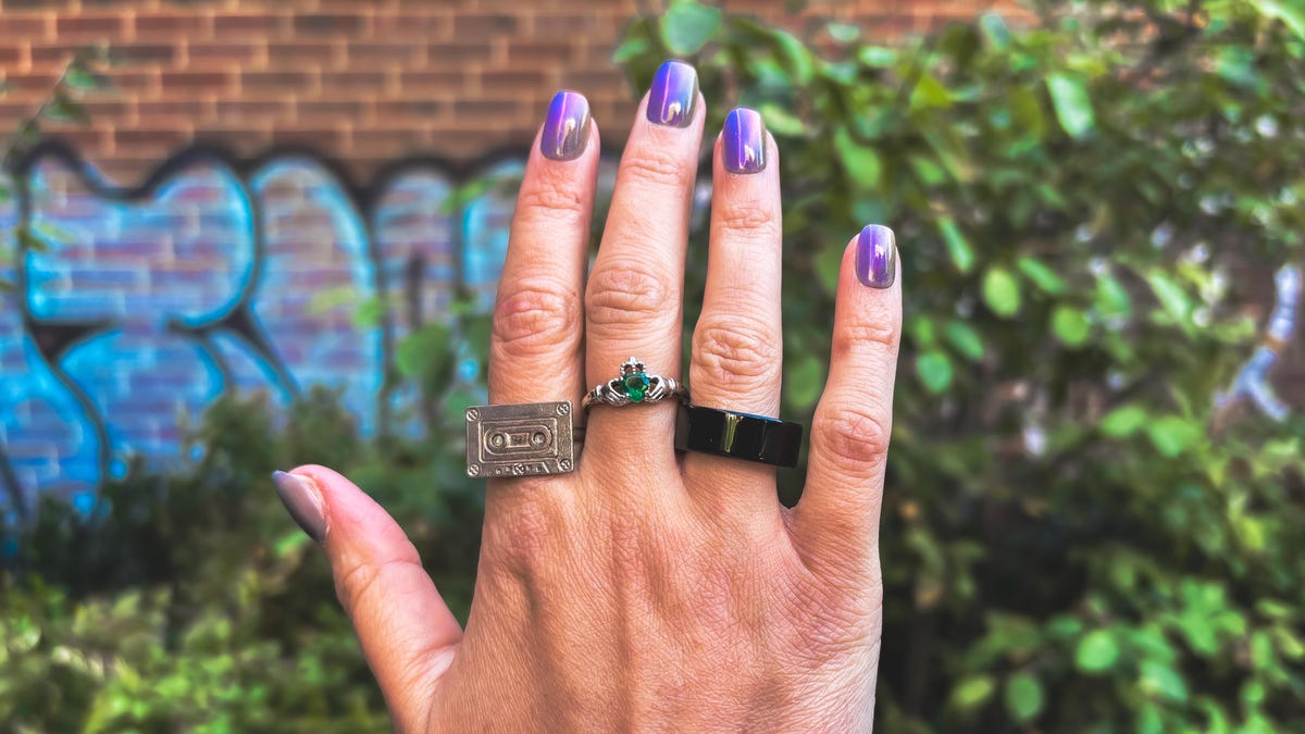 A woman's hand with rings on it in front of a wall