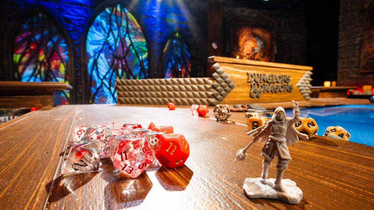 A shot of a gaming table with dice and a character figurine in the foreground.