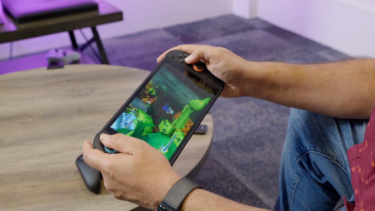 Hands holding a Switch 2 console and playing a Sonic game on the screen