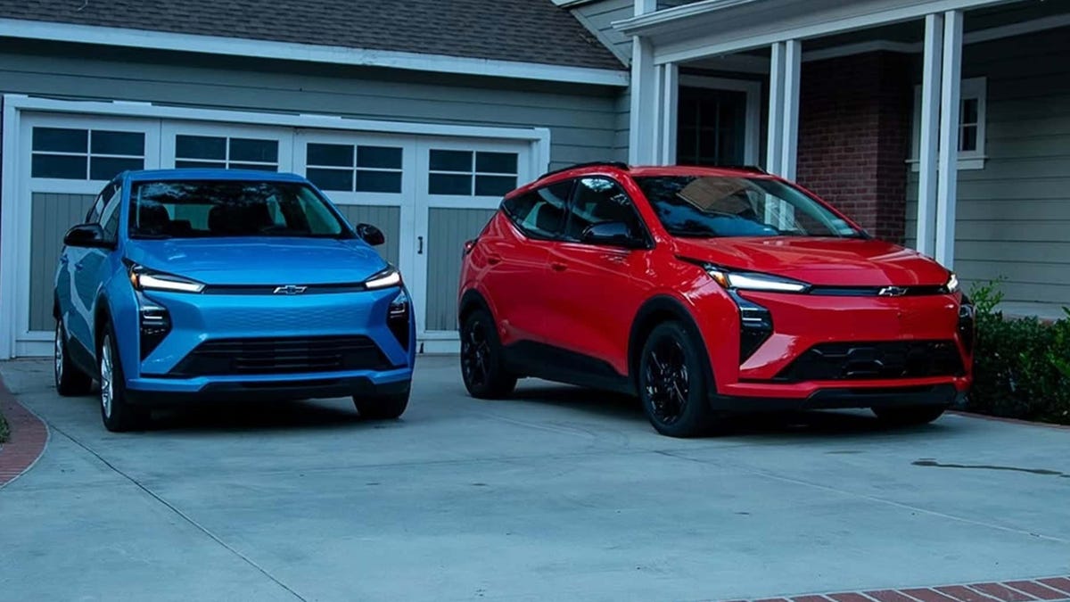 The 2027 Chevrolet Bolt in blue (left) and red sit on a driveway.