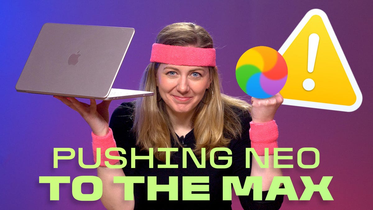 The writer holds up her pink MacBook Neo in one hand. The other hand holds graphics of the Mac's spinning pinwheel and a warning symbol.