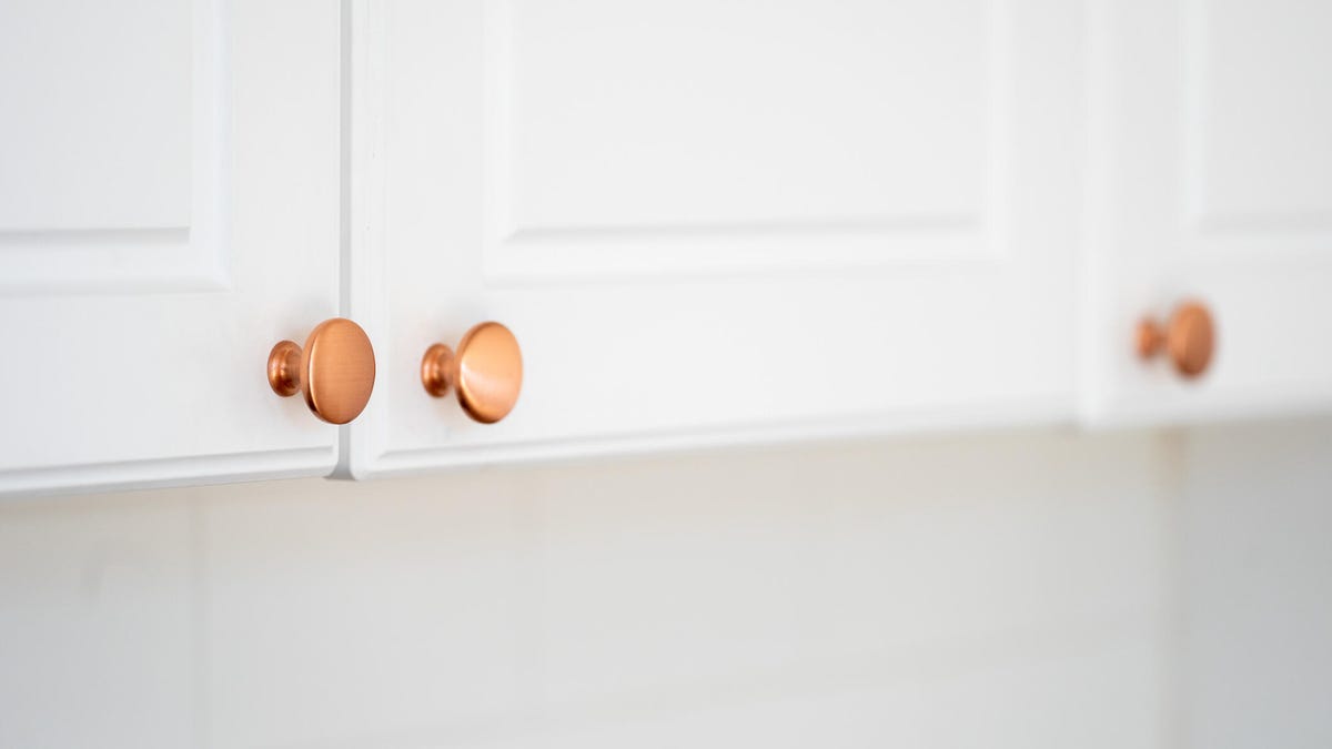 Round copper door handles on a white cabinet in a classic style