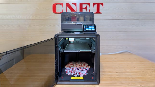 A 3d printer with a bunch of Pokemon coins on the base.