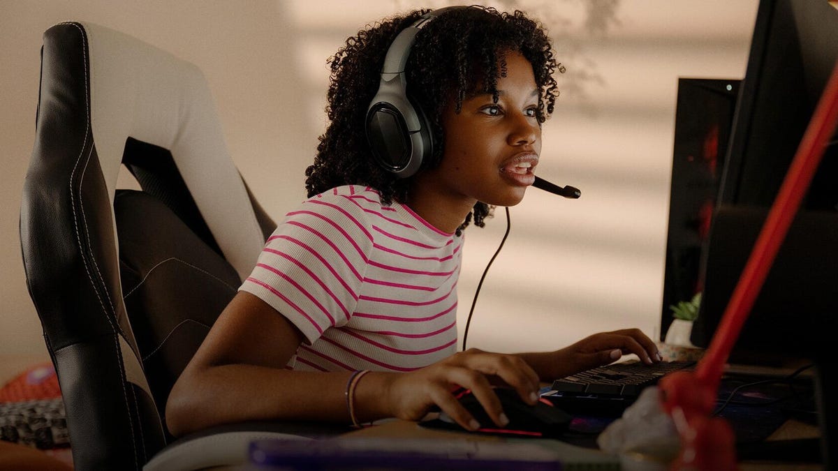 Young girl sitting at a desk with her gaming headset on
