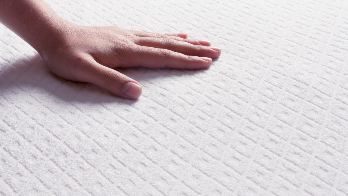 A hand feeling a mattress to see if it's cooling