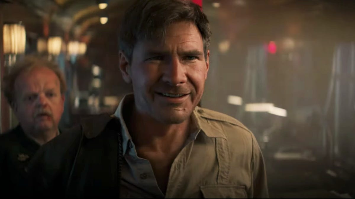 A younger Harrison Ford as Indiana Jones smiling in a train