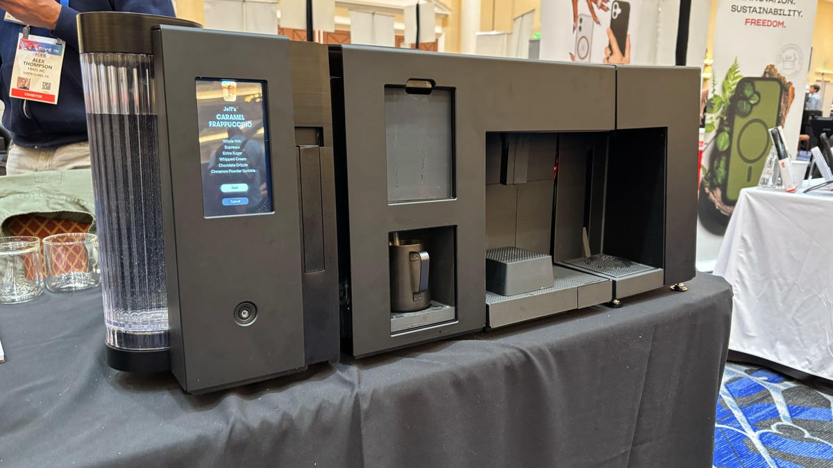 A black coffee robot sitting on a conference room table.
