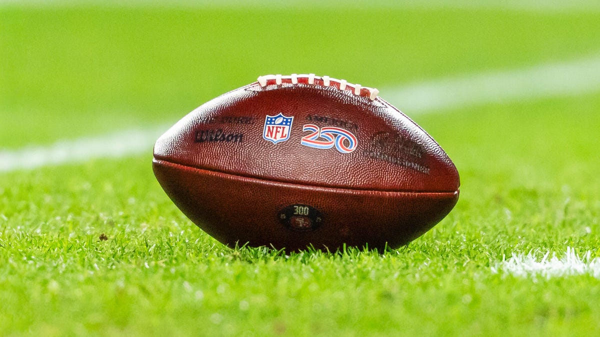 A football with an NFL logo sitting on a football field