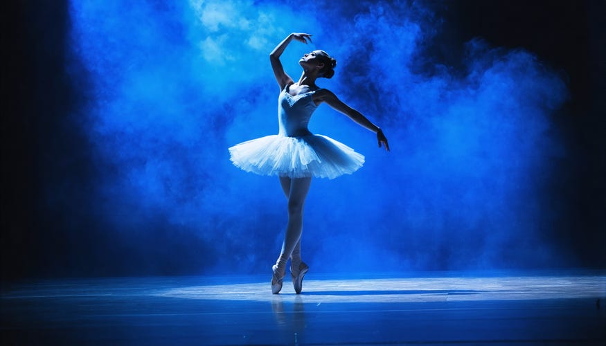 ballerina on pointe shoes on an empty stage dramatically lit with blue lights and smoke