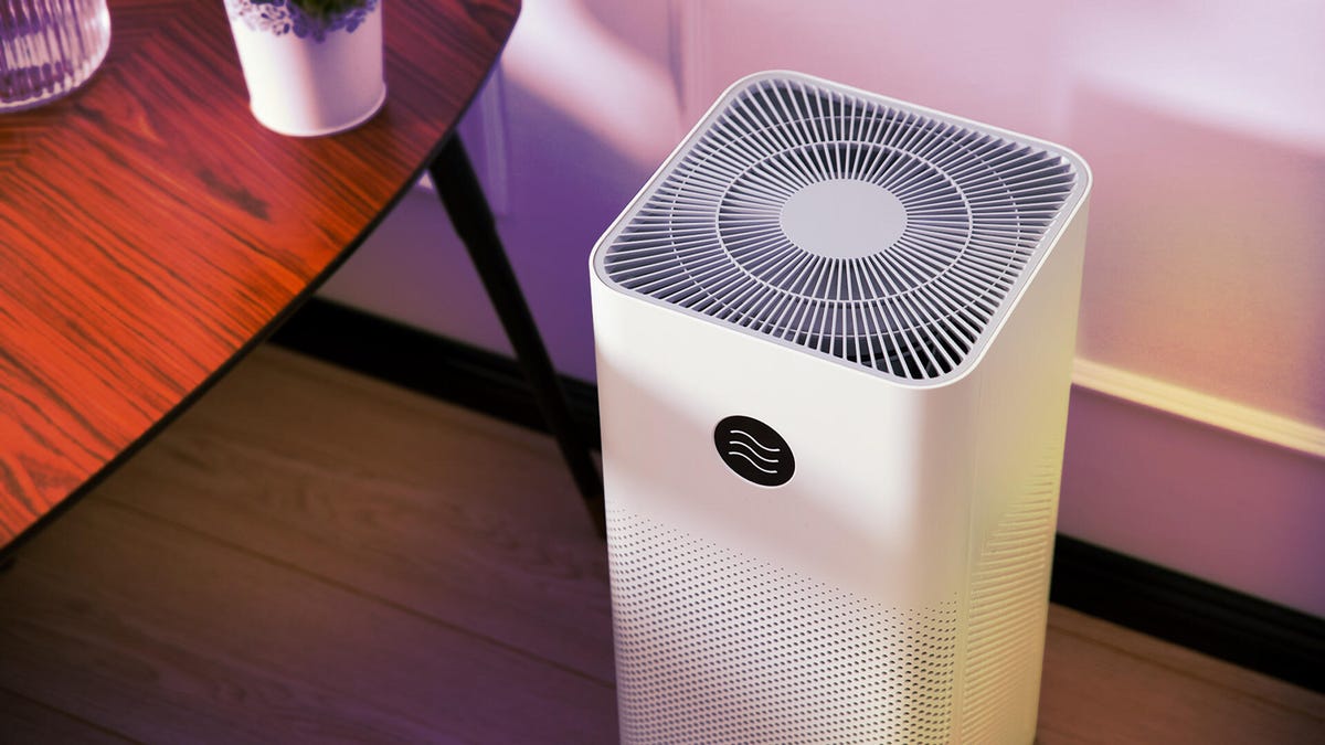 A woman reads a book to a little boy as they lie in bed and the Shark HE601 Air Purifier 6 rests nearby.
