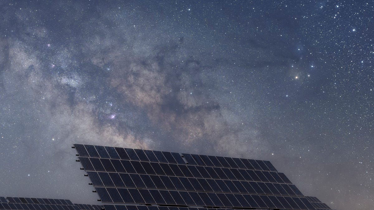 Solar panels sit under a night sky.