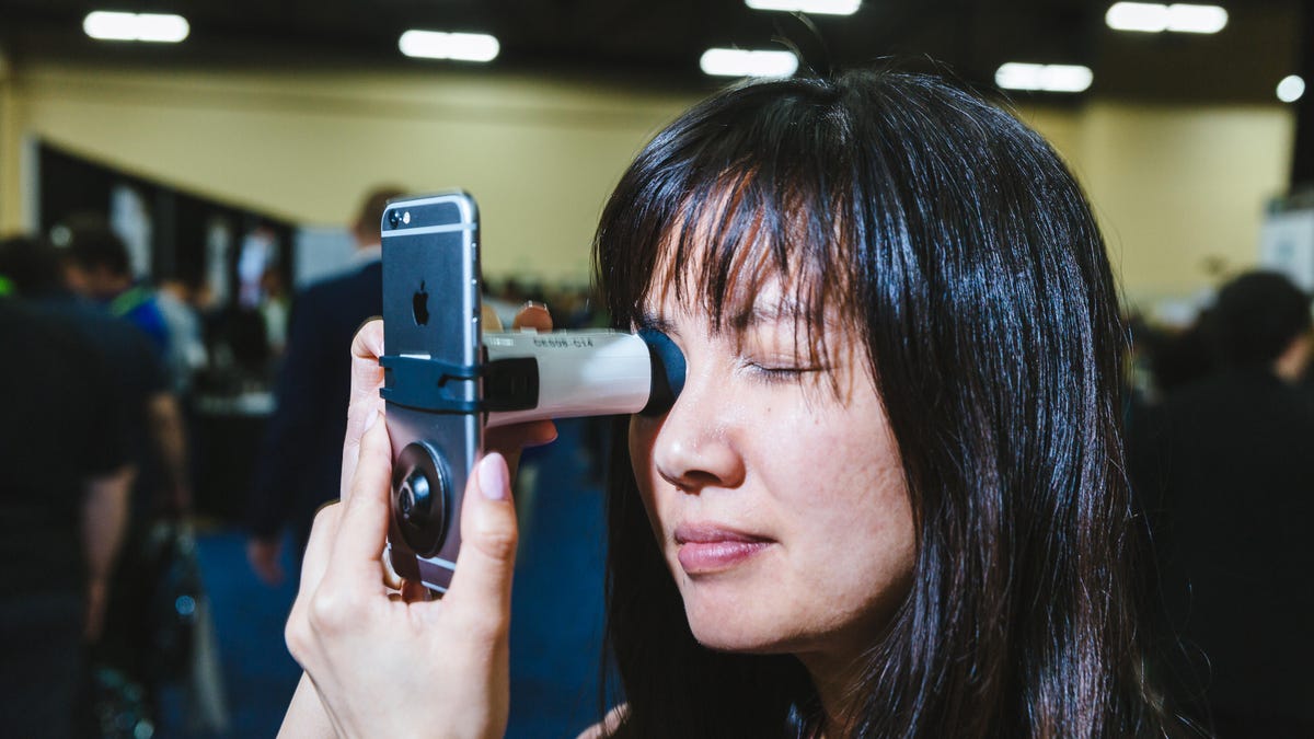 woman using EyeQue VisionCheck device and smartphone to test vision