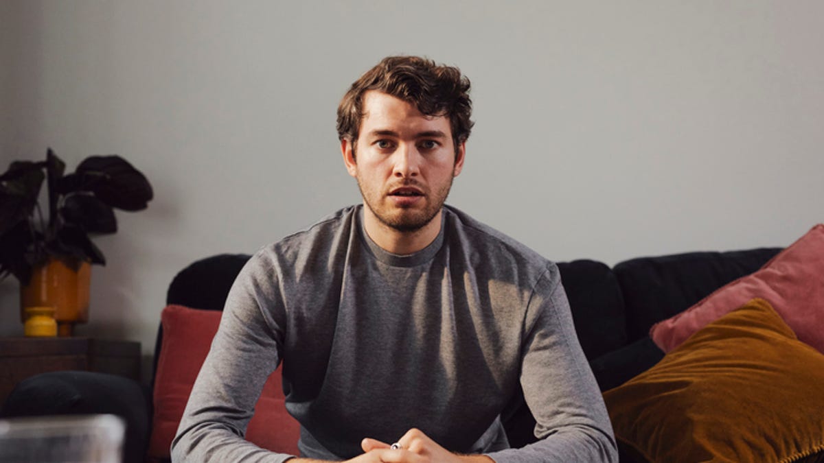 Young man, sitting on a couch and looking worried.