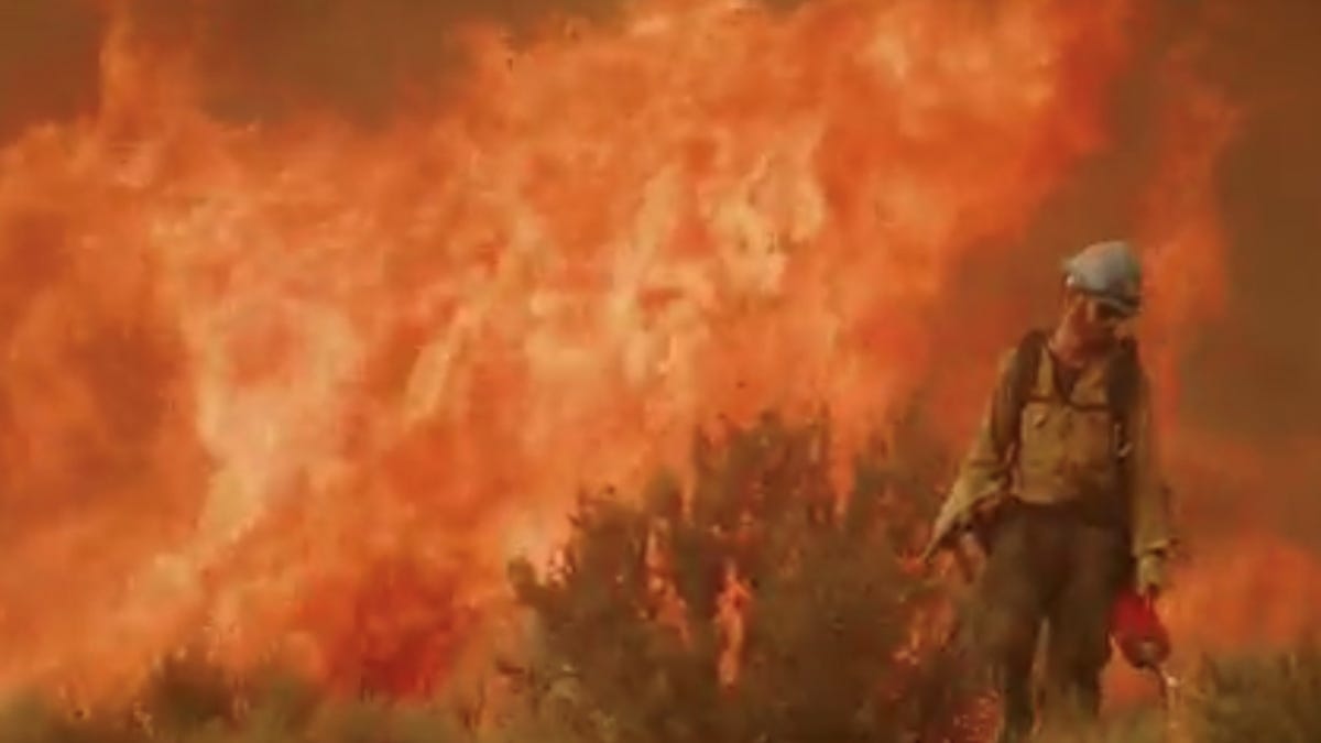 A Carson Hotshot with a wildfire in the background