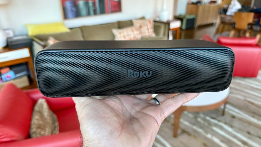 A person holds in their hand a Roku Streambar Se to demonstrate its size.