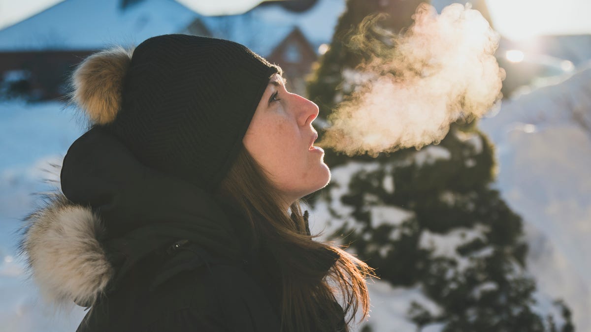 Person in winter snow with a cloud of visible breath.