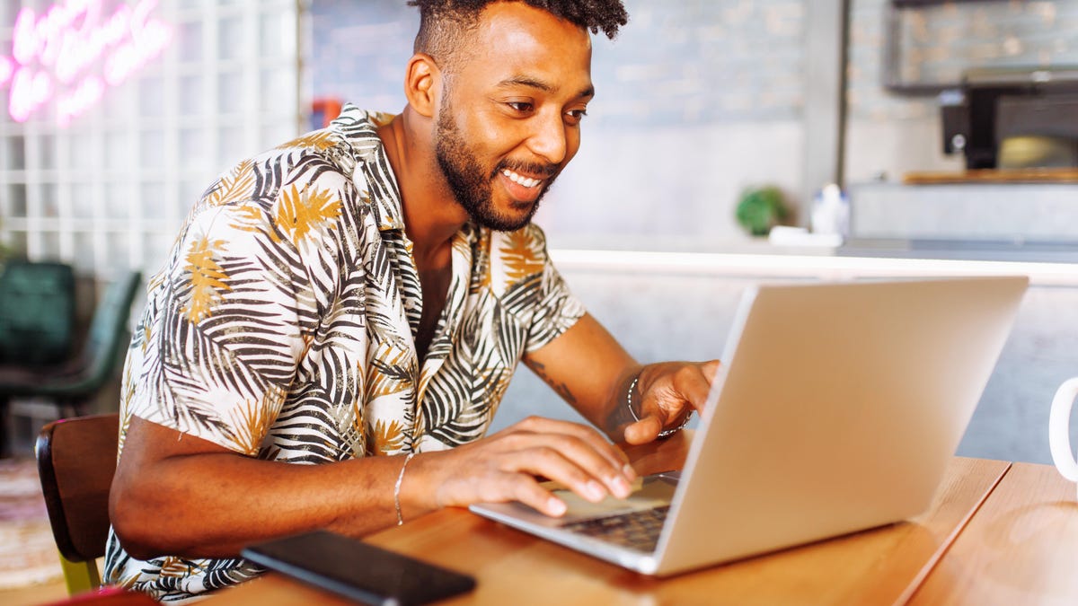 Man leaning over laptop computer on a desk.