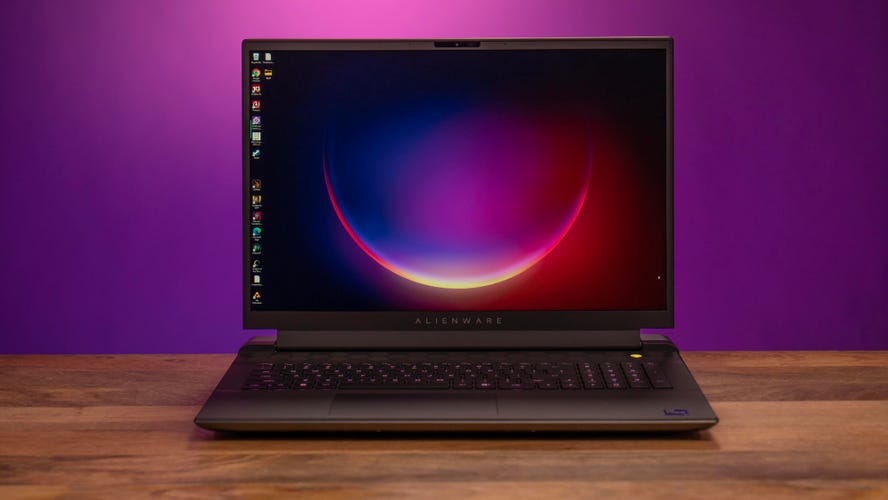 Alienware m18 R2 open, facing you, on a wood table with a magenta and purple background