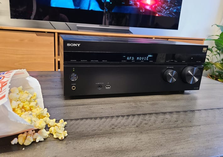 The Sony STR-AN1000 receiver on a wooden coffee table with popcorn in front of a TV.