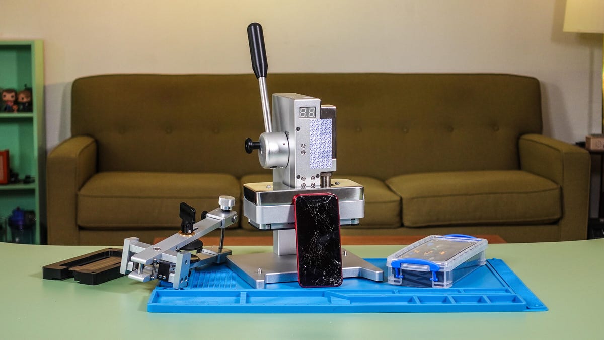 All the tools needed to fix an iPhone SE's broken screen laid out on a table, with a sofa in the background.