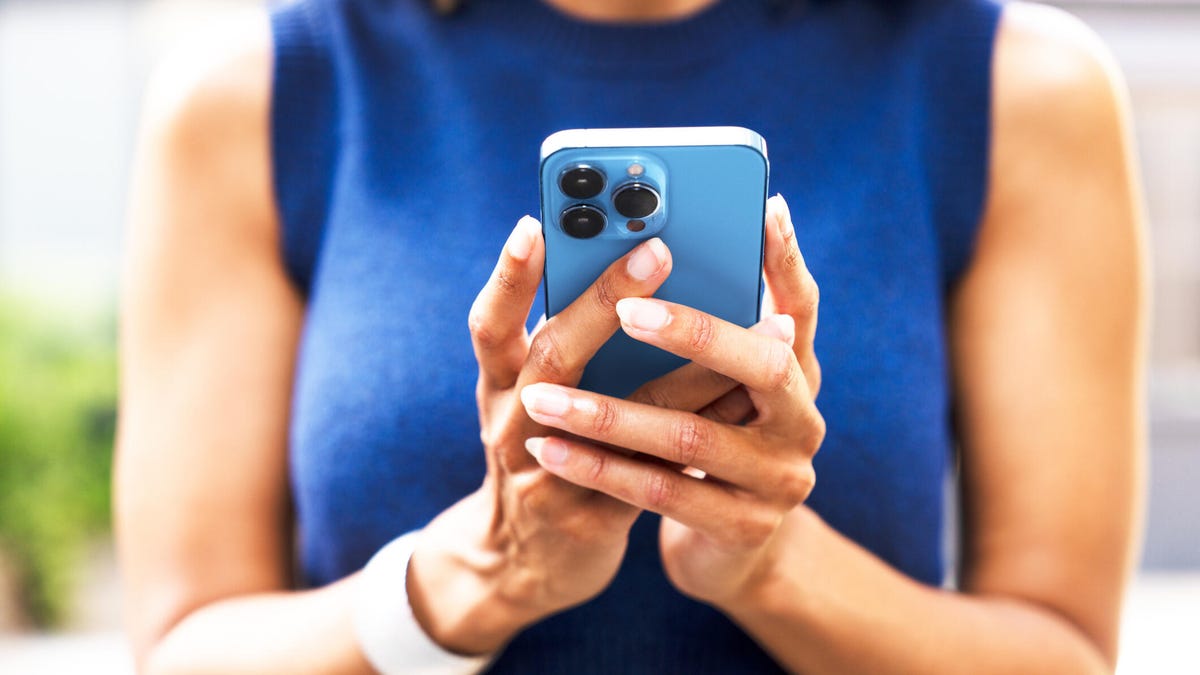 A woman holding an iPhone in both hands.