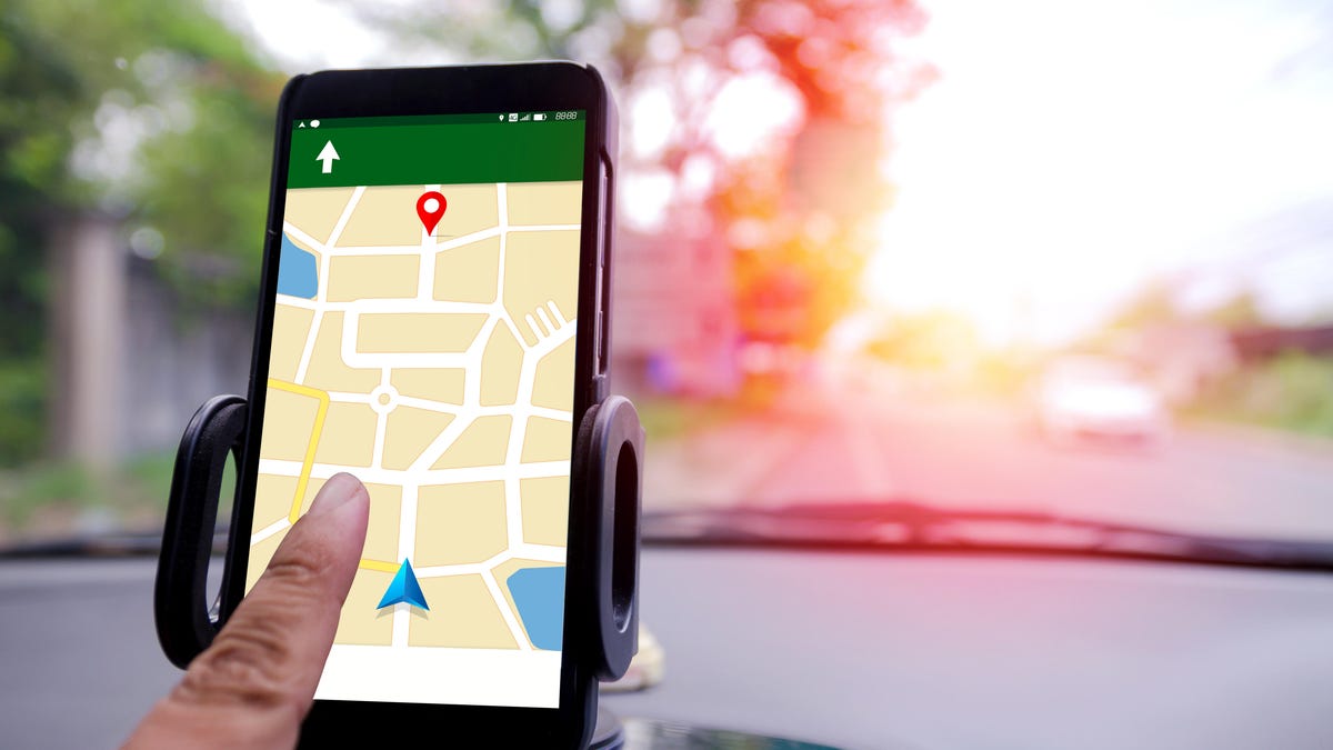 Close-Up Of Hand Operating Global Positioning System On Smart Phone In Car