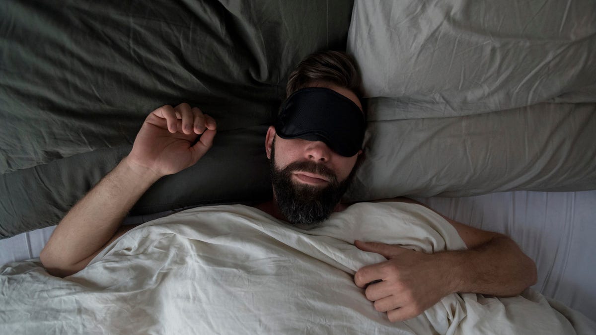 High angle view of man wearing sleep mask while sleeping on bed at home