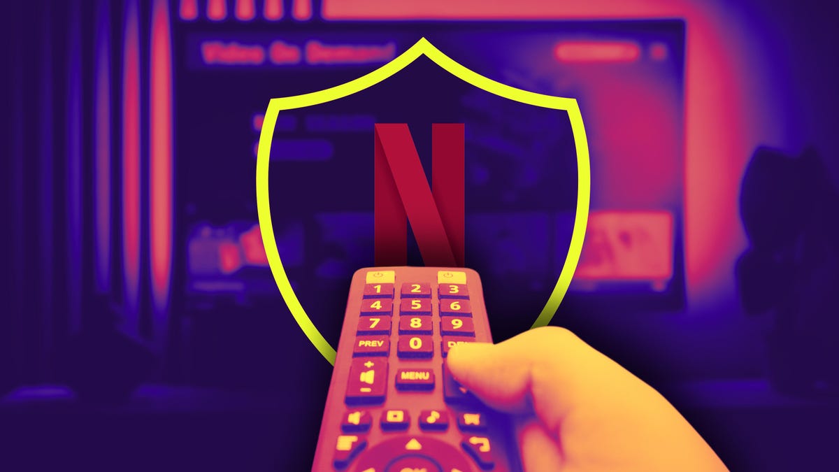Hand holding a TV remote pointing towards a shield with the Netflix "N" logo with a blurred living room TV background