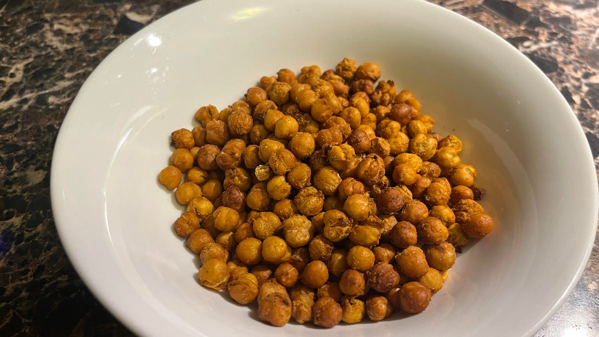 A white bowl filled with air-fried chickpeas is on a kitchen counter