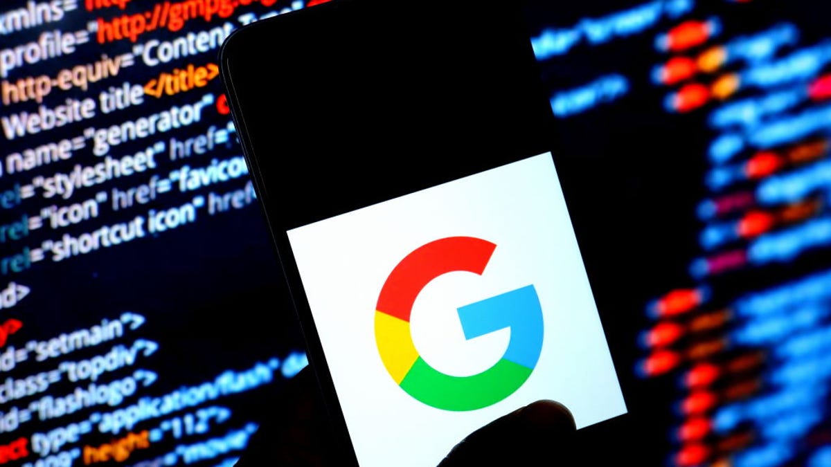 An image of the Google logo displayed on an Android phone with computer code in the background