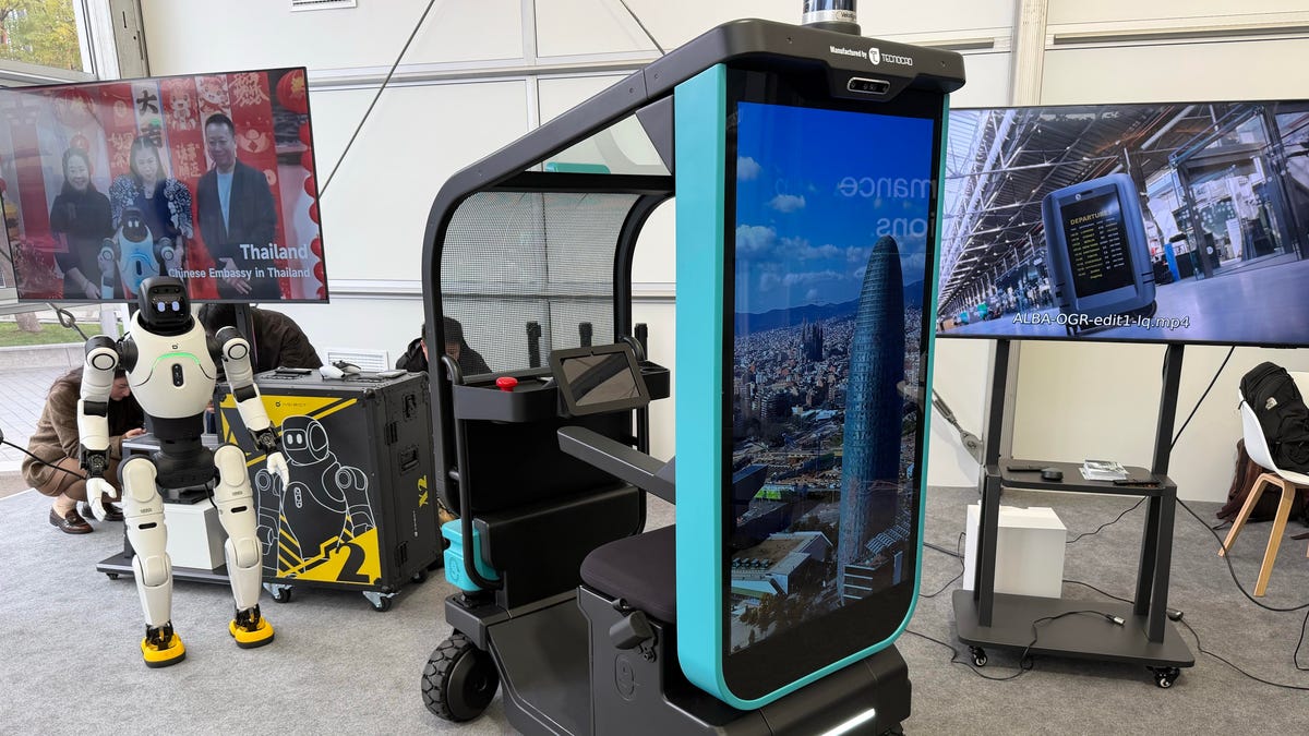 An autonomous small vehicle with a robot in the background