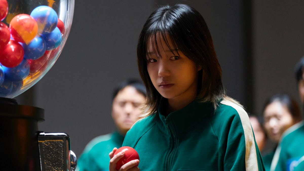 woman in green tracksuit holding red ball