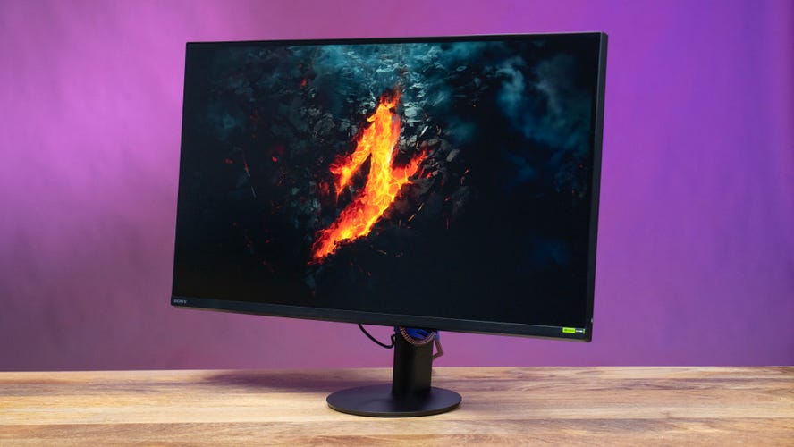 Monitor angled left on a wooden surface against a purple and magenta background