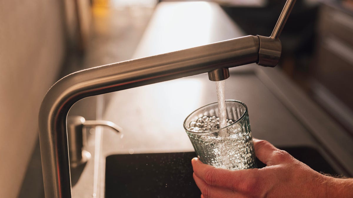person filling glass with tap water