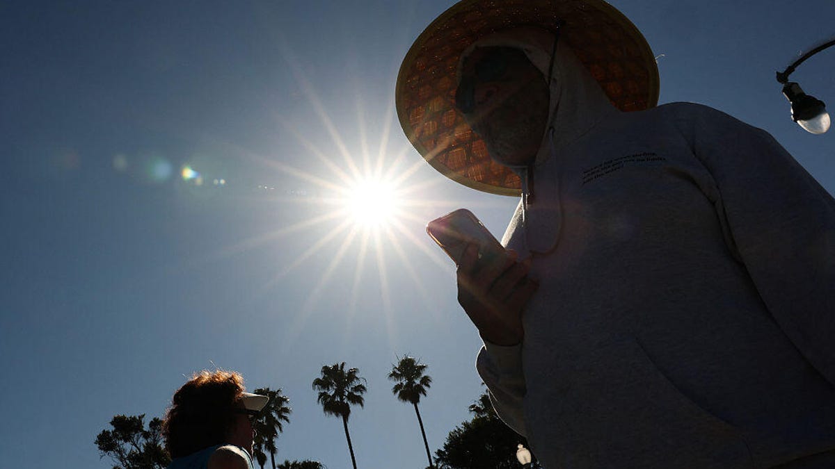 A person in a hat is silhouetted by the overhead sun.