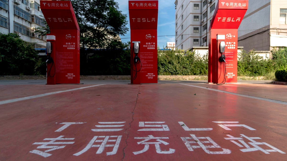 A vacant Tesla charging station on a parking lot beside a