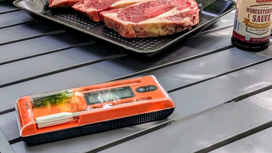 ThermoPro Twin Spike sitting on a table with steak in the background.