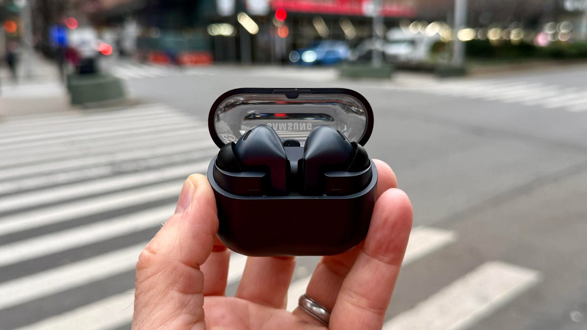 holding the black galaxy earbuds on a street in New York