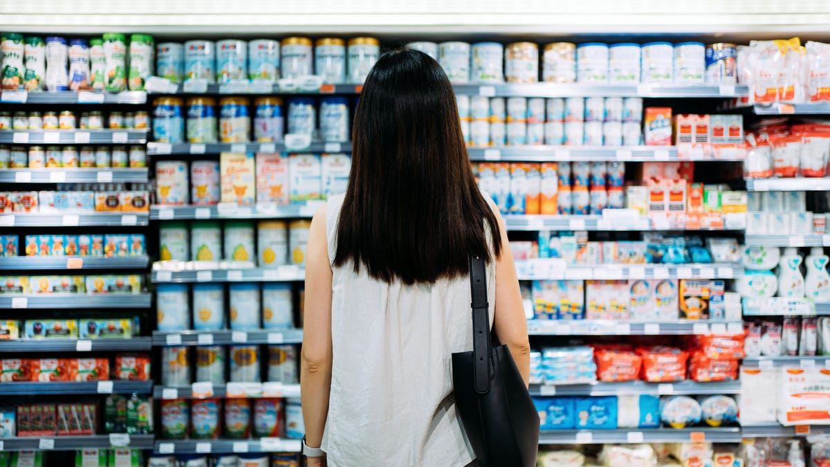 Woman stands in front of dairy aisle in grocery store