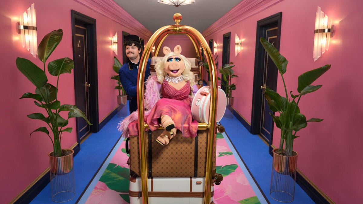 Muppet Miss Piggy gets a ride on a luggage cart in a scene from Booking.com's Super Bowl commercial.