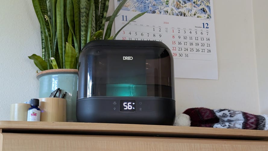 black Dreo humidifier with a wall calendar, plant and hat nearby